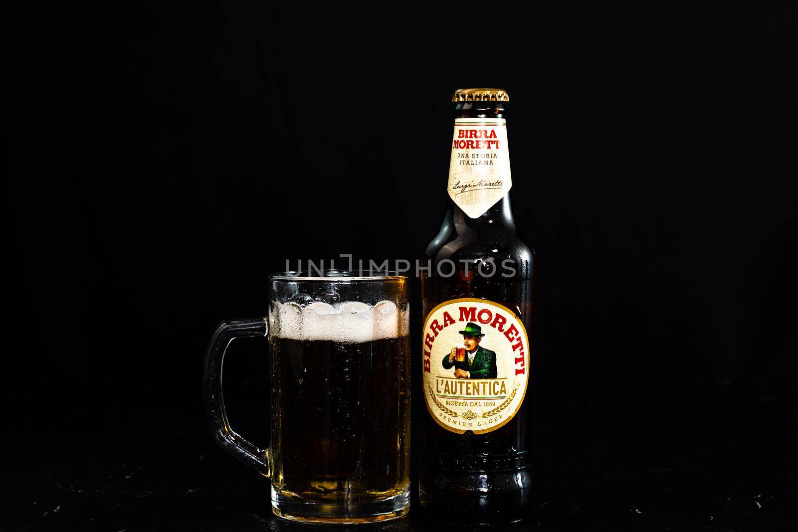 Can of Birra Morreti beer and beer glass on dark background. Illustrative editorial photo shot in Bucharest, Romania, 2021 by vladispas