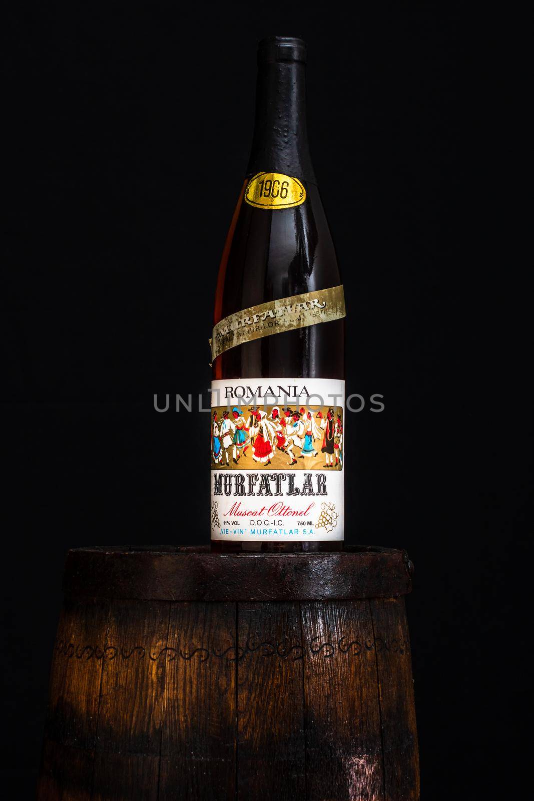 Vintage Murfatlar wine bottle on wooden barrel with dark background. Illustrative editorial photo Bucharest, Romania, 2021 by vladispas