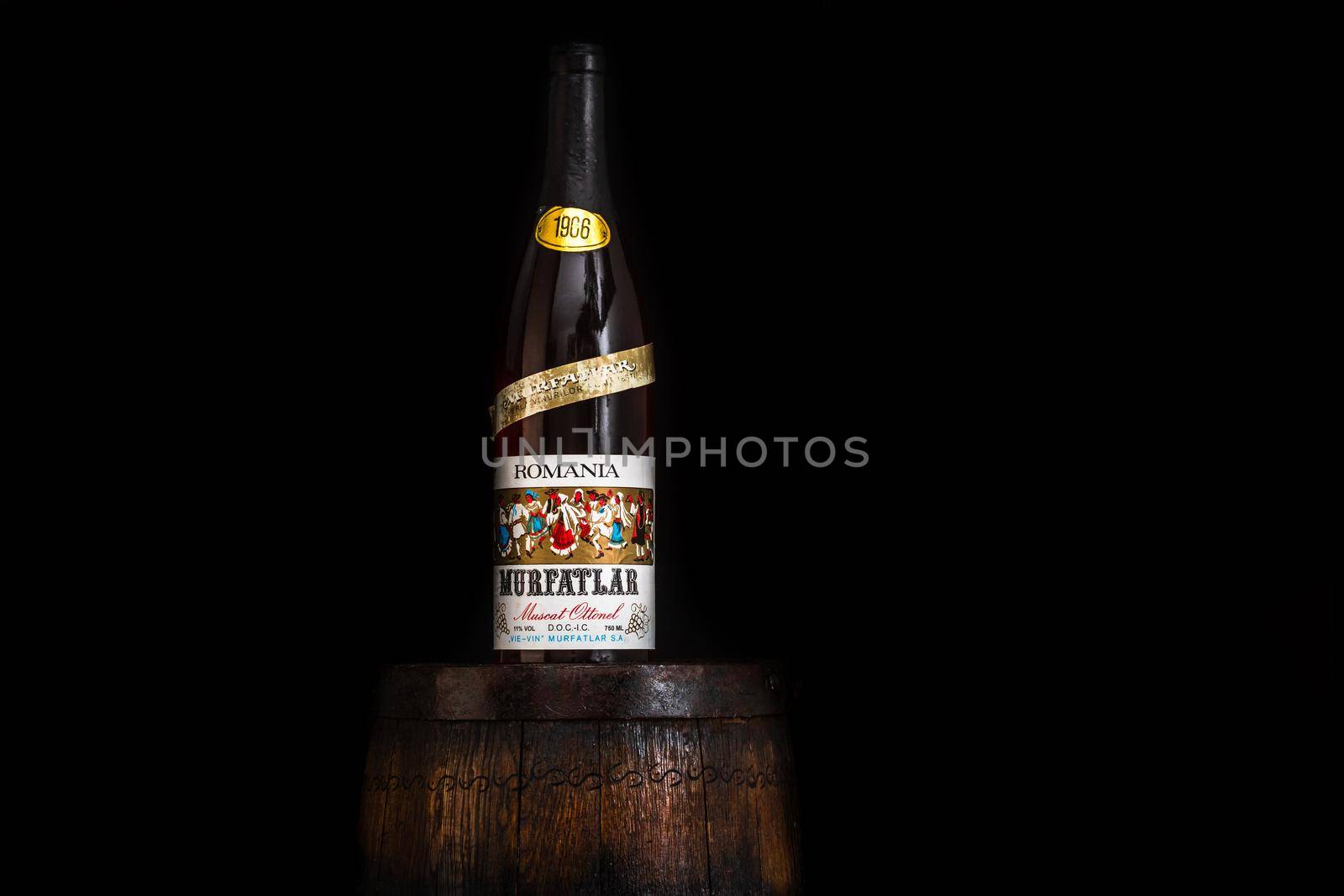 Vintage Murfatlar wine bottle on wooden barrel with dark background. Illustrative editorial photo Bucharest, Romania, 2021