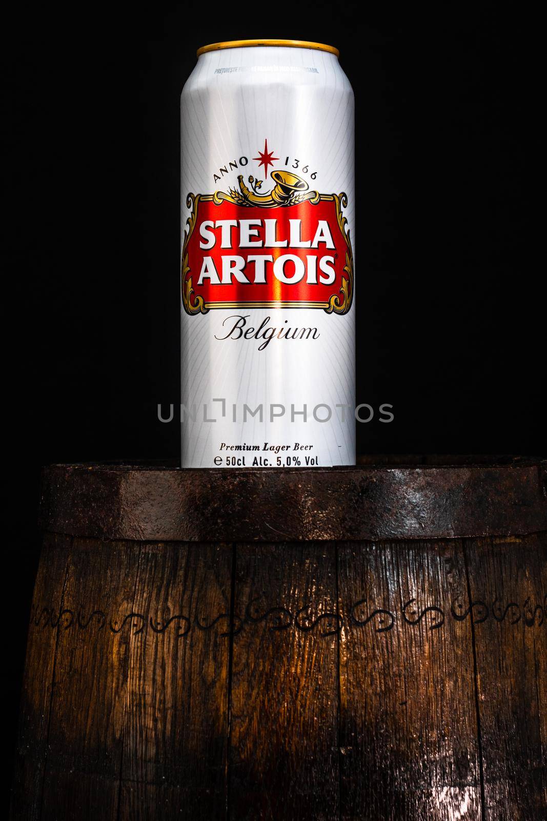 Can of Stella Artois beer on beer barrel with dark background. Illustrative editorial photo Bucharest, Romania, 2021 by vladispas