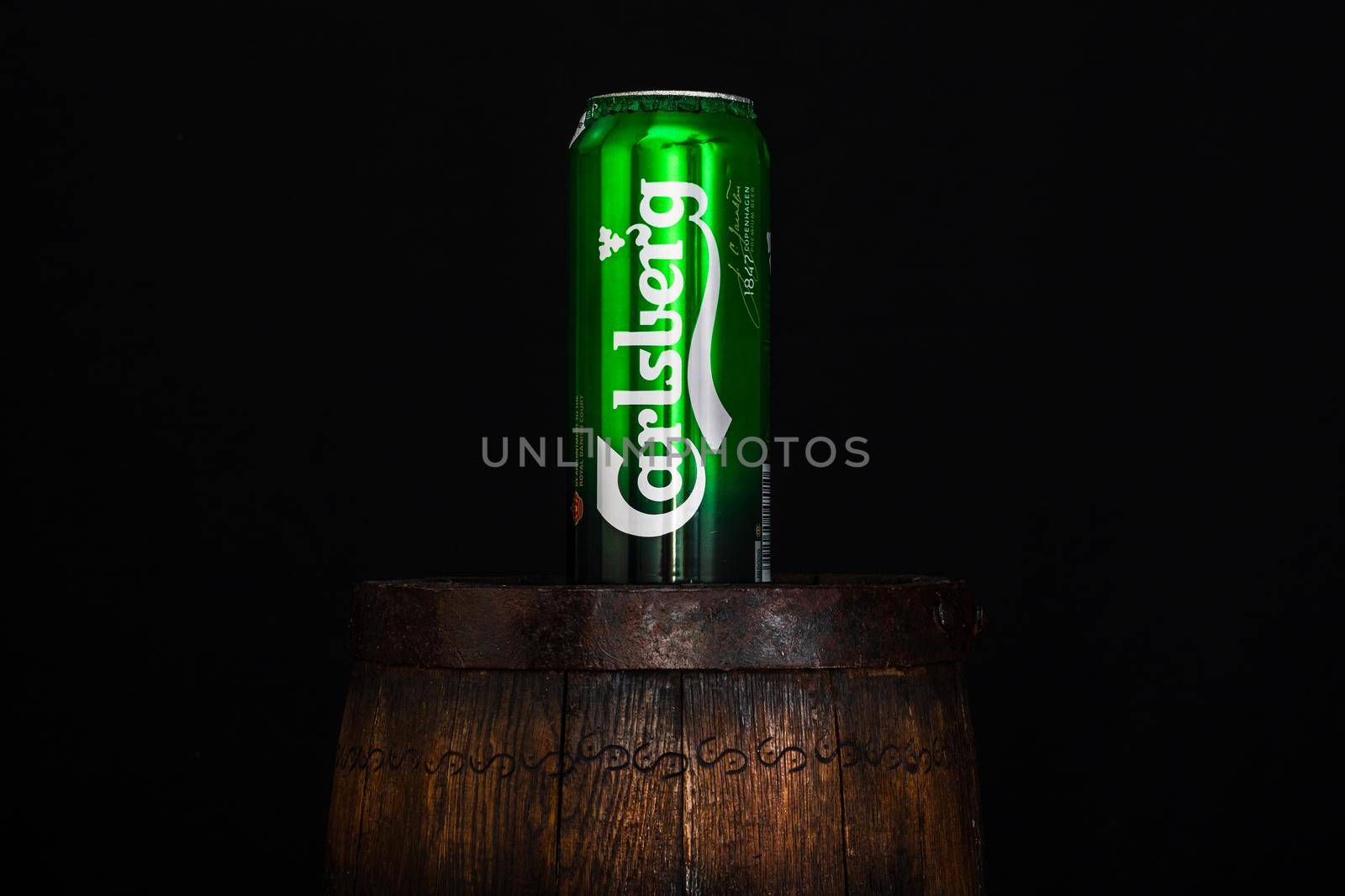 Can of Carsberg beer on beer barrel with dark background. Illustrative editorial photo shot in Bucharest, Romania, 2021