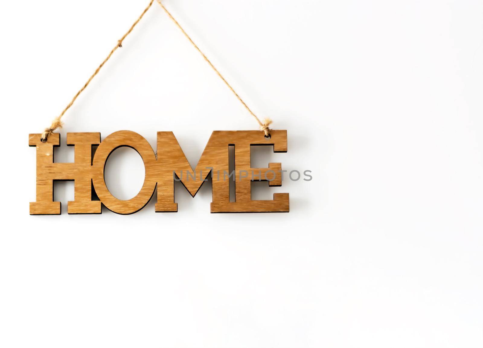 Home wood decorative lettering hanging on a white wall. Home Interior and copy-space