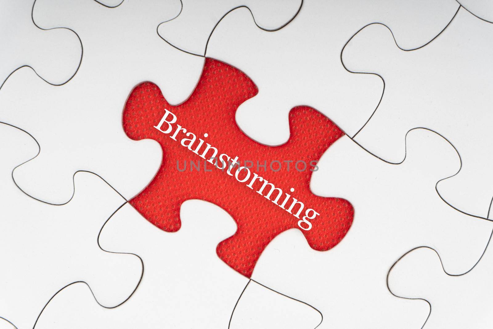 BRAINSTORMING text with jigsaw puzzle on red background. Business and Motivation Concept