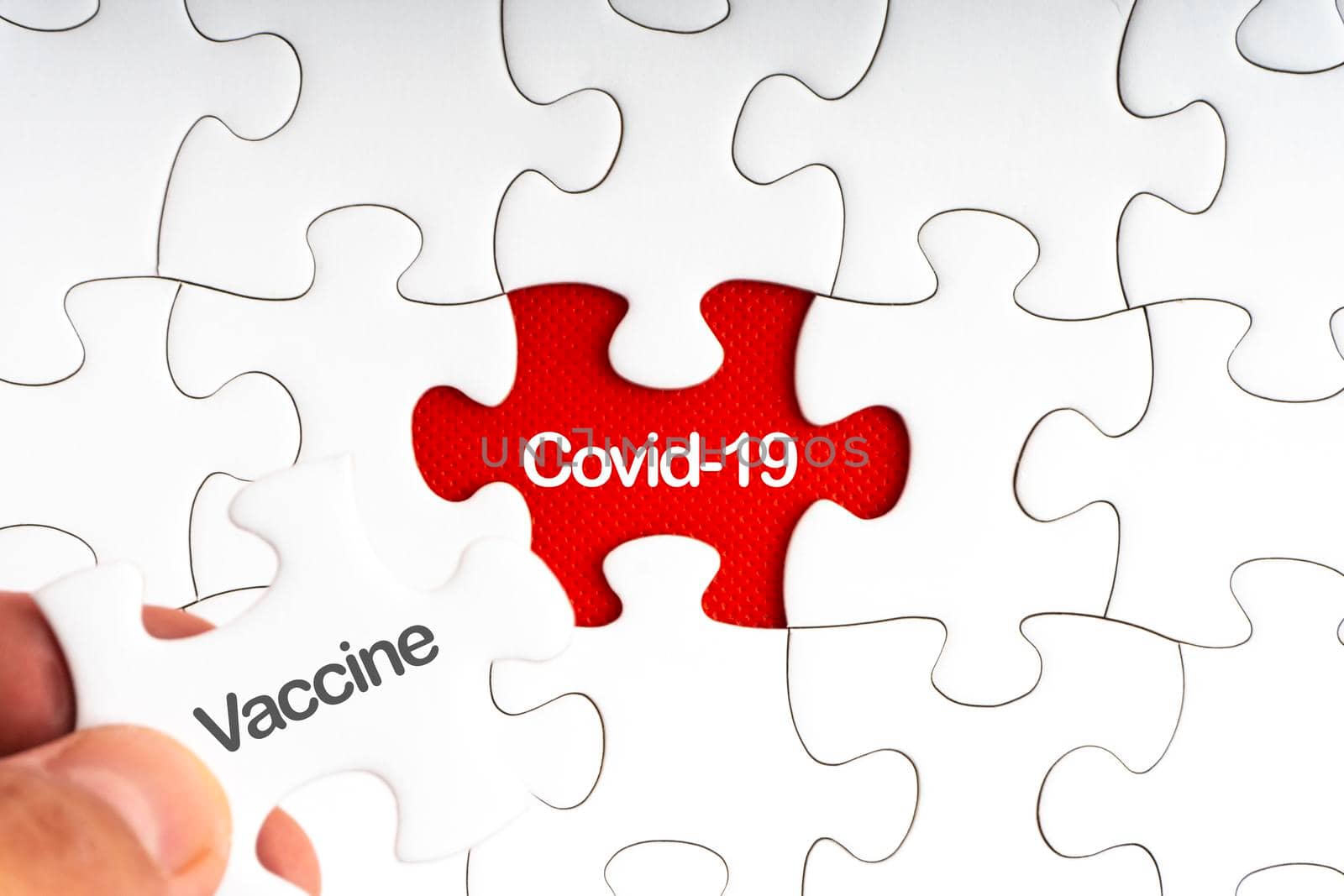 COVID-19 VACCINE text with jigsaw puzzle on red background. by silverwings