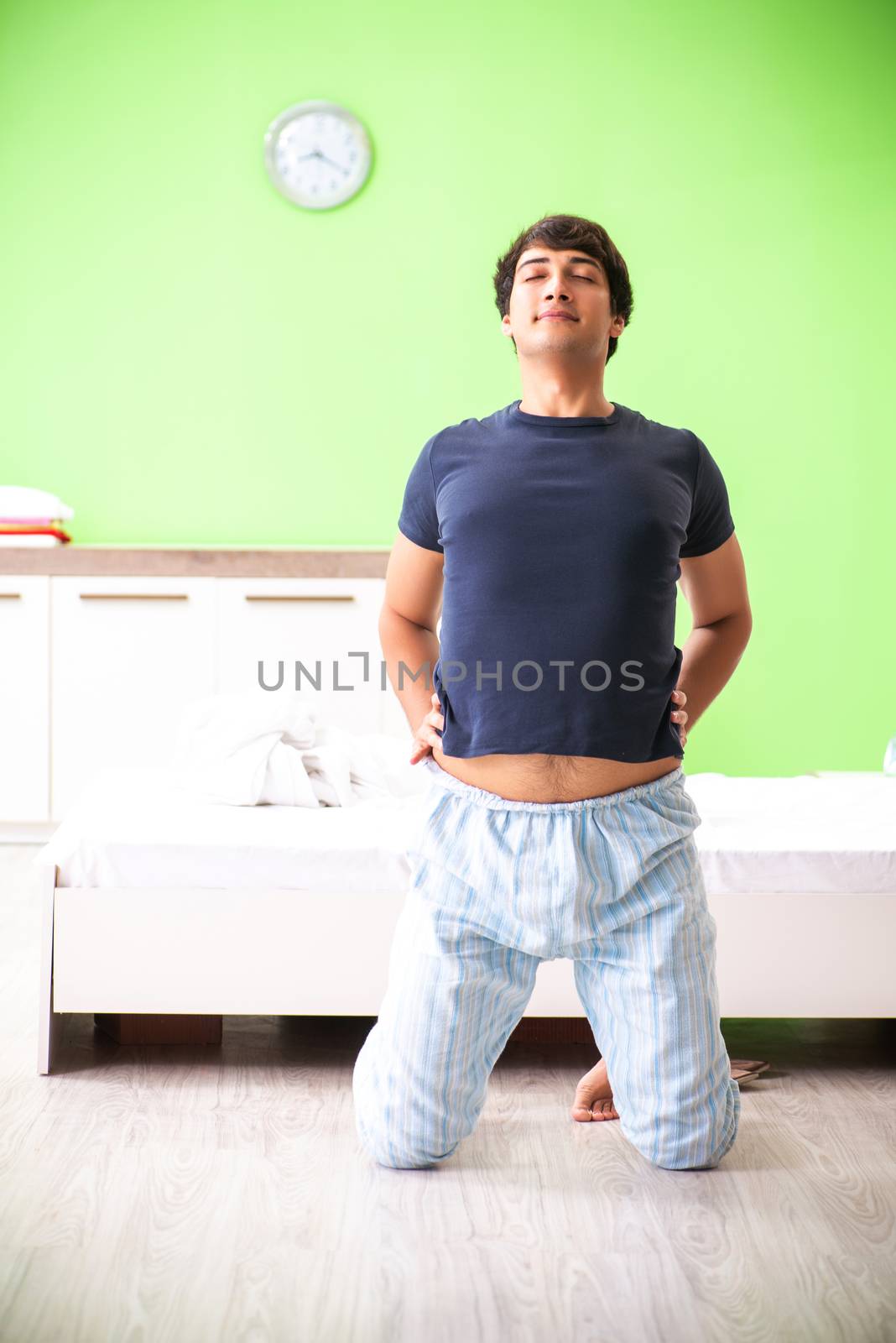 Young man in pajamas doing morning exercises 