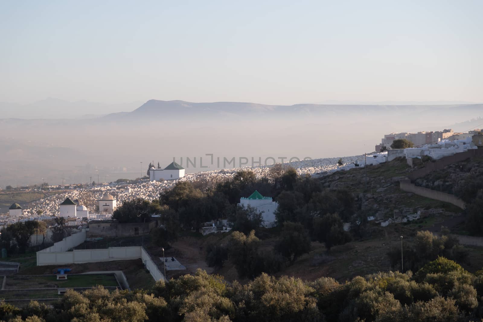 Bab Mahrouk Cemetery Fes Morocco with atmospheric mist and mountains behind by kgboxford