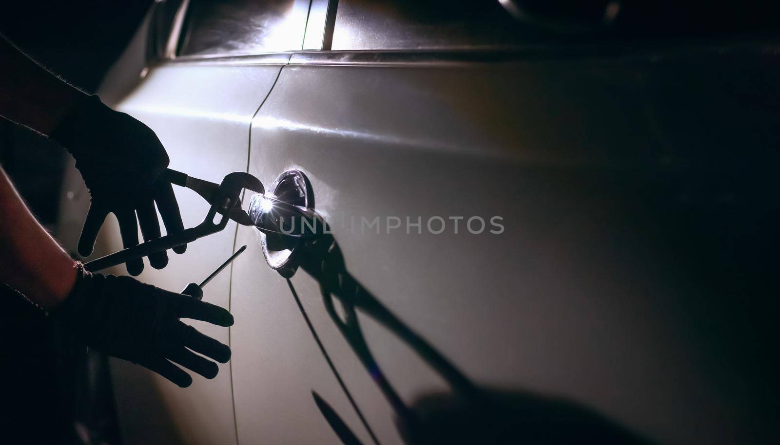 Car thief using a tool to break into a car