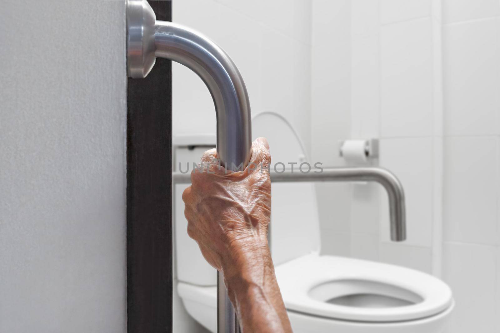 Elderly woman holding on handrail in bathroom