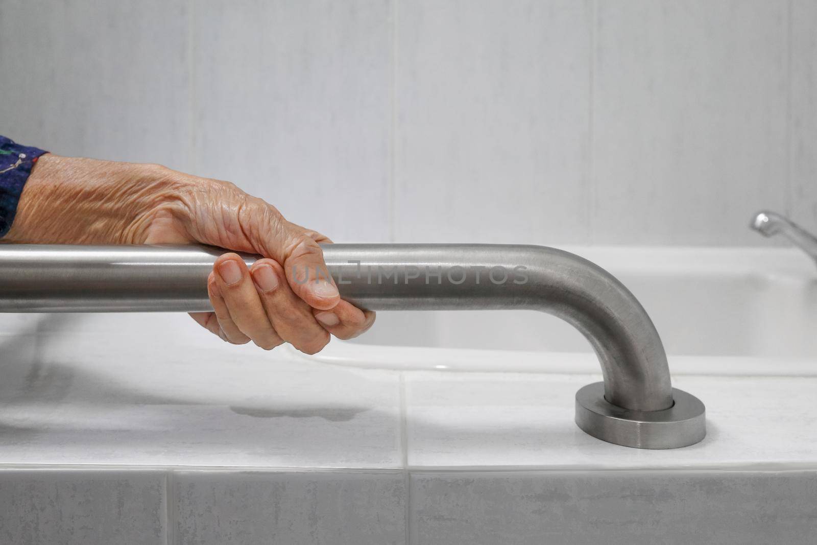 Elderly woman holding on handrail in bathroom