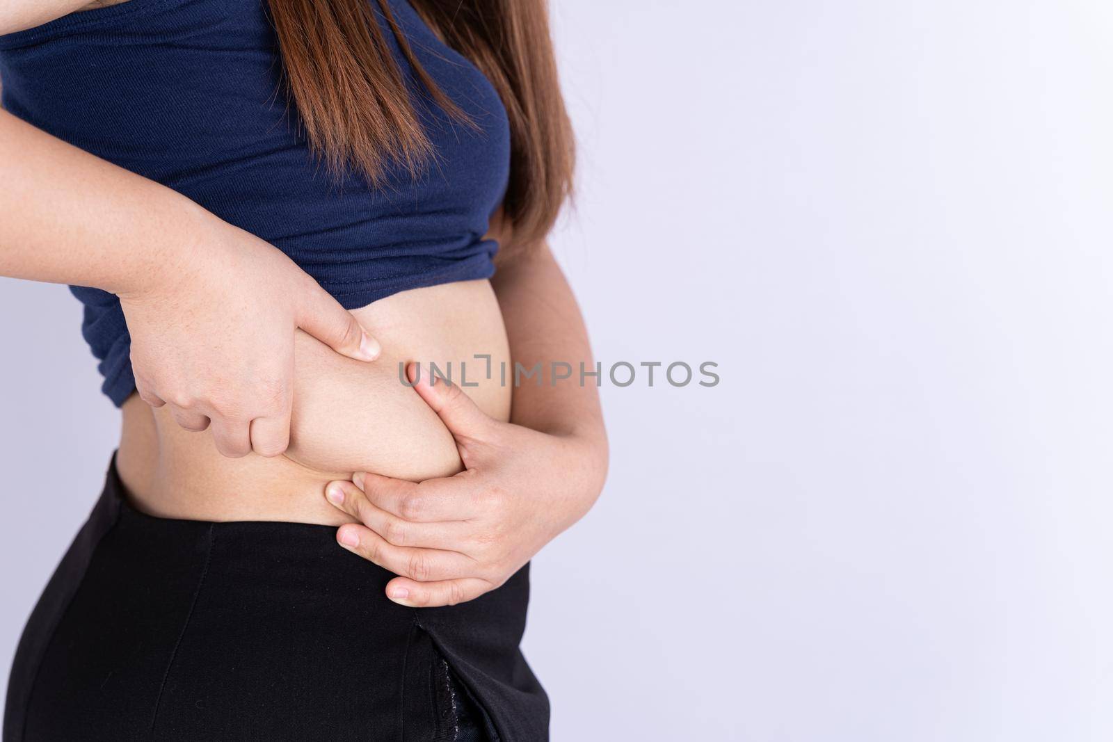 Fat woman holding excessive fat belly isolated grey background.