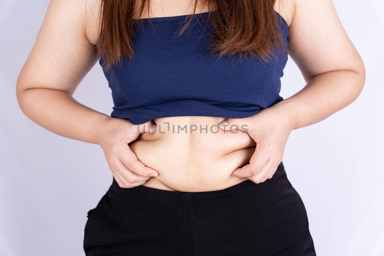 Fat woman holding excessive fat belly isolated grey background.