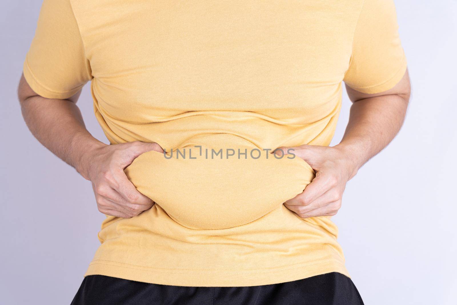 Fat man holding excessive fat belly isolated grey background. by mikesaran