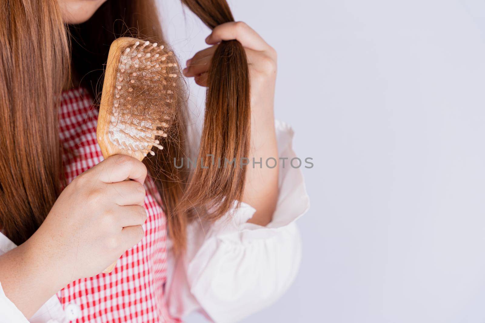 Closeup hand holding comb and hair fall problem isolated grey background.