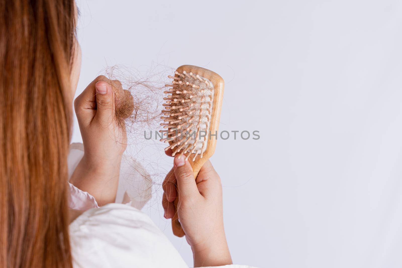 Closeup hand holding comb and hair fall problem isolated grey background. by mikesaran