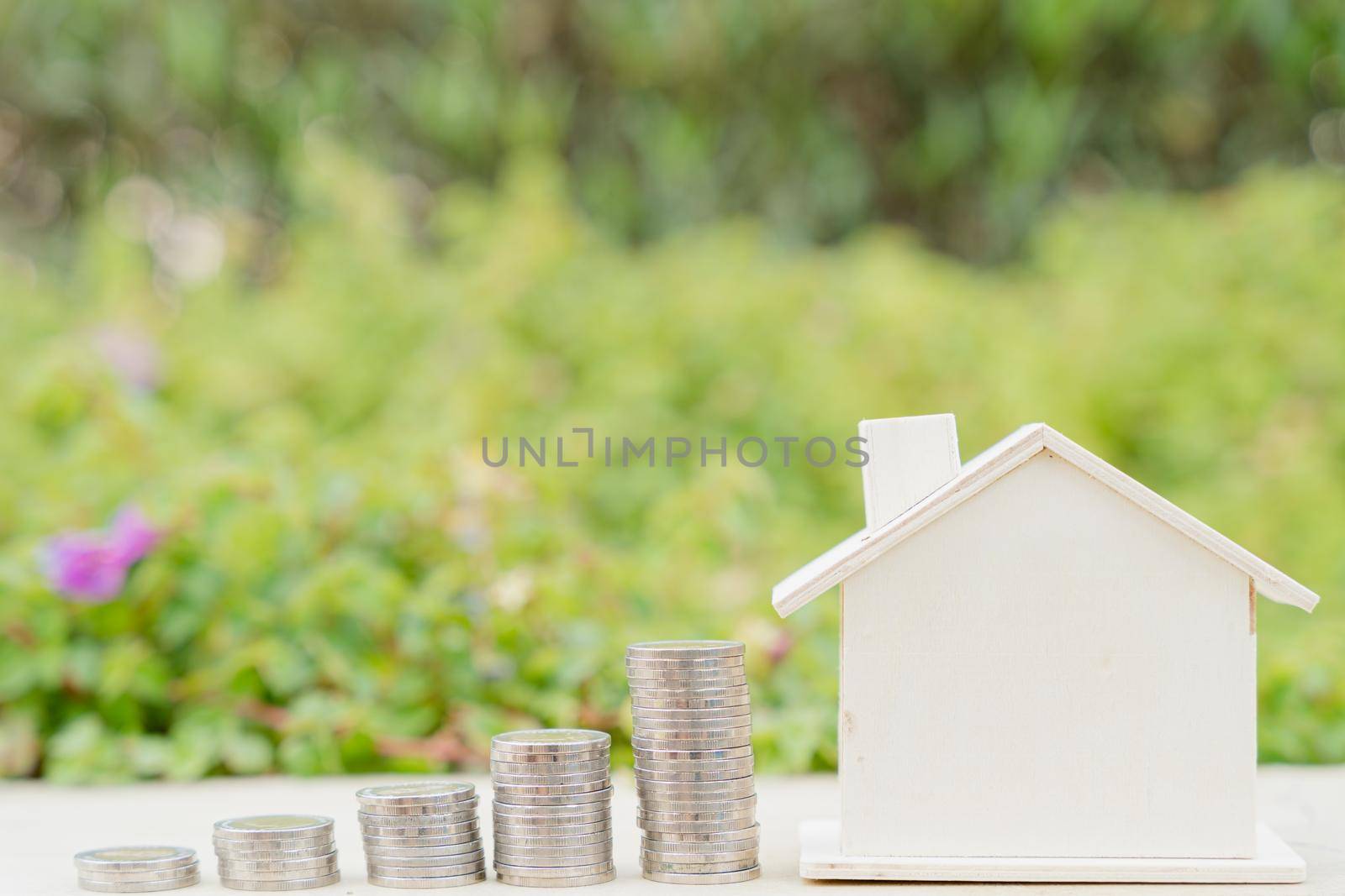 House and stack coins on blurred green natural background. Property investment and house mortgage financial concept. by mikesaran