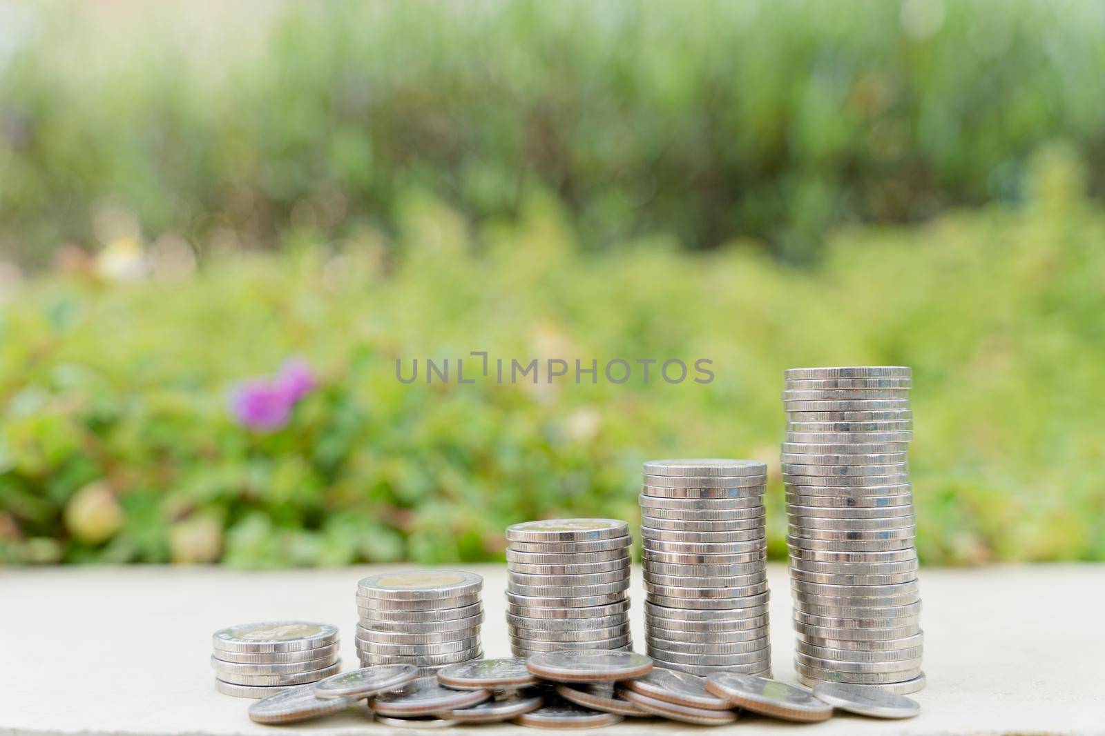 Stack coins on blurred green natural background. Property investment and house mortgage financial concept.