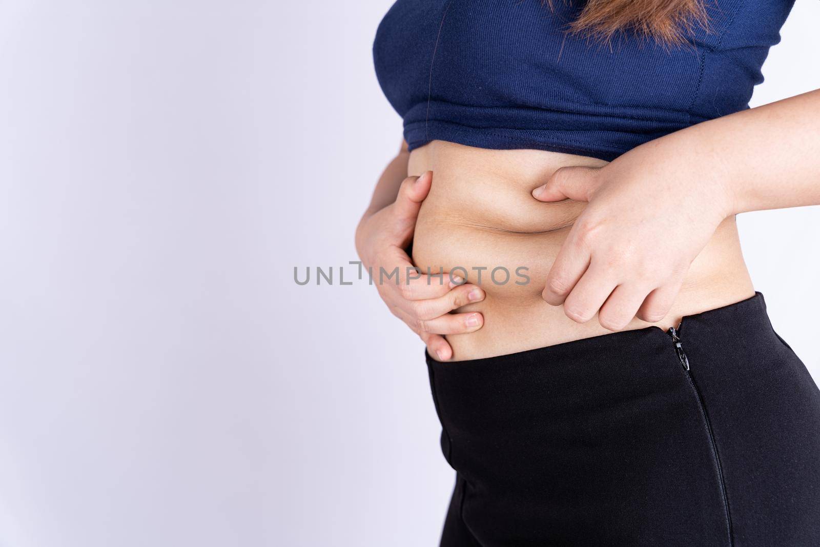 Fat woman holding excessive fat belly isolated grey background.