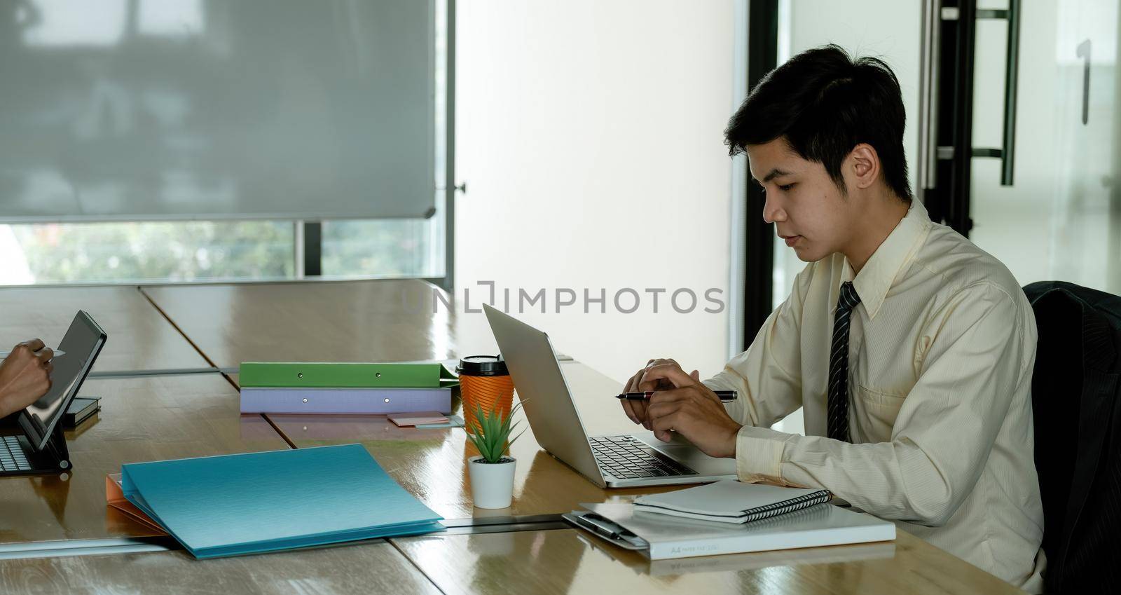 Male office worker browsing in laptop for necessary information, Young asian businessman working at office.