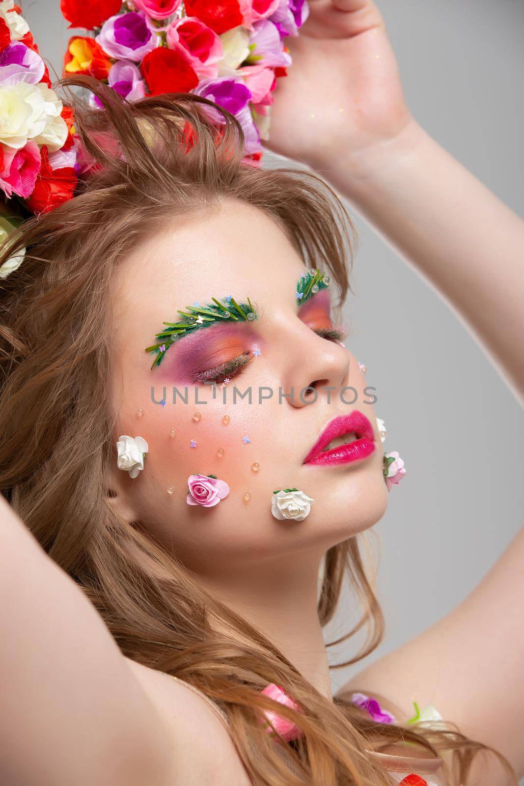 Portrait of a beautiful girl with floral makeup. Summer girl in flowers. The face of a luxurious model in the image of spring. The concept of eyebrow and eyelash extensions.