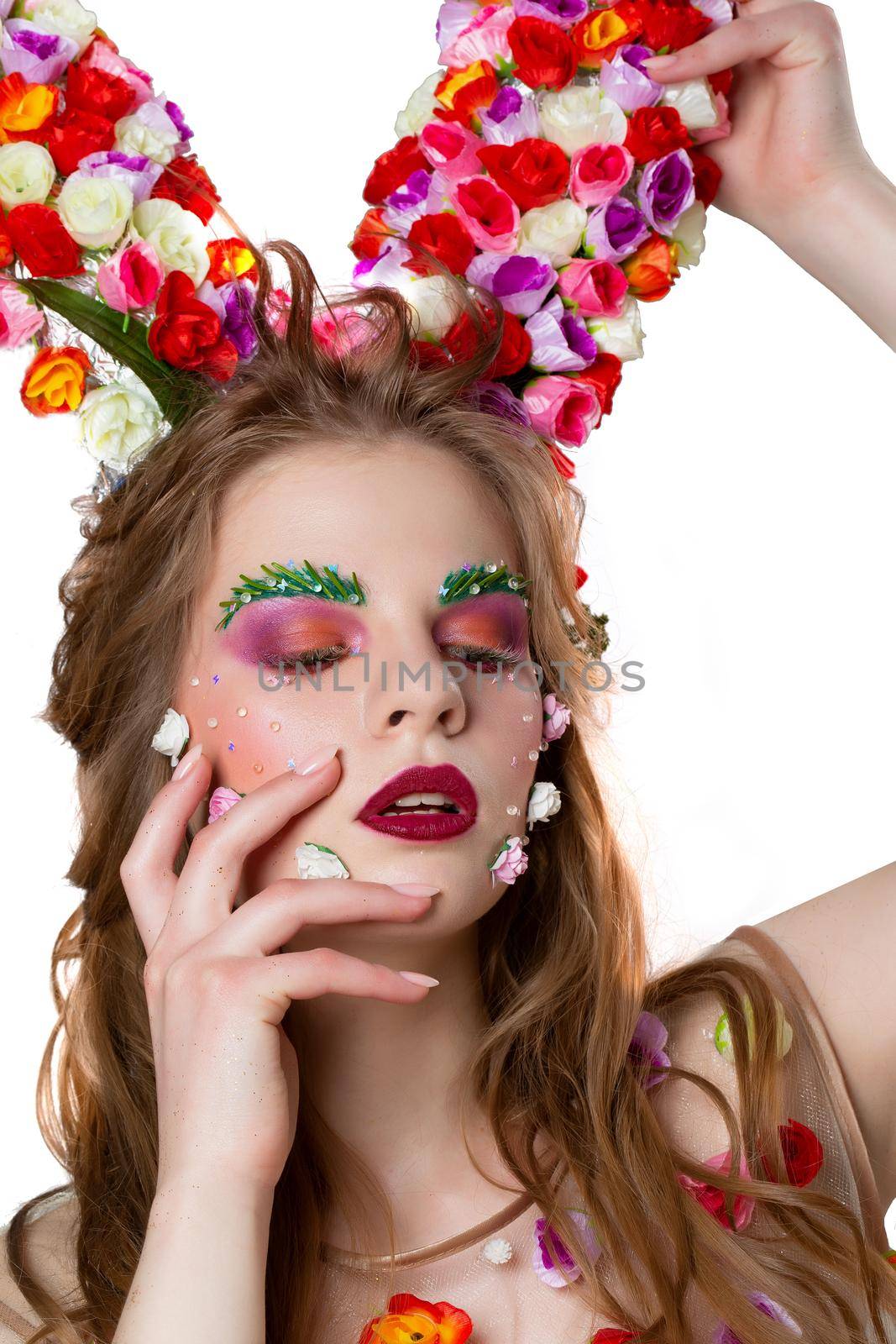 Fairytale spring girl model with floral horns and bright makeup on a white background.