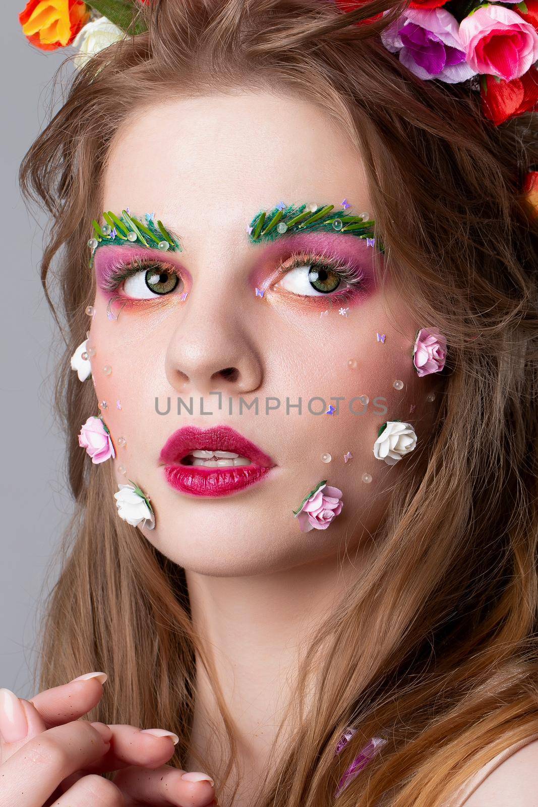 Close-up face of a beautiful girl with fairytale make-up. Spring girl. Gorgeous beauty with extended eyebrows and eyelashes. Natural cosmetics concept. The image of spring. by Sviatlana