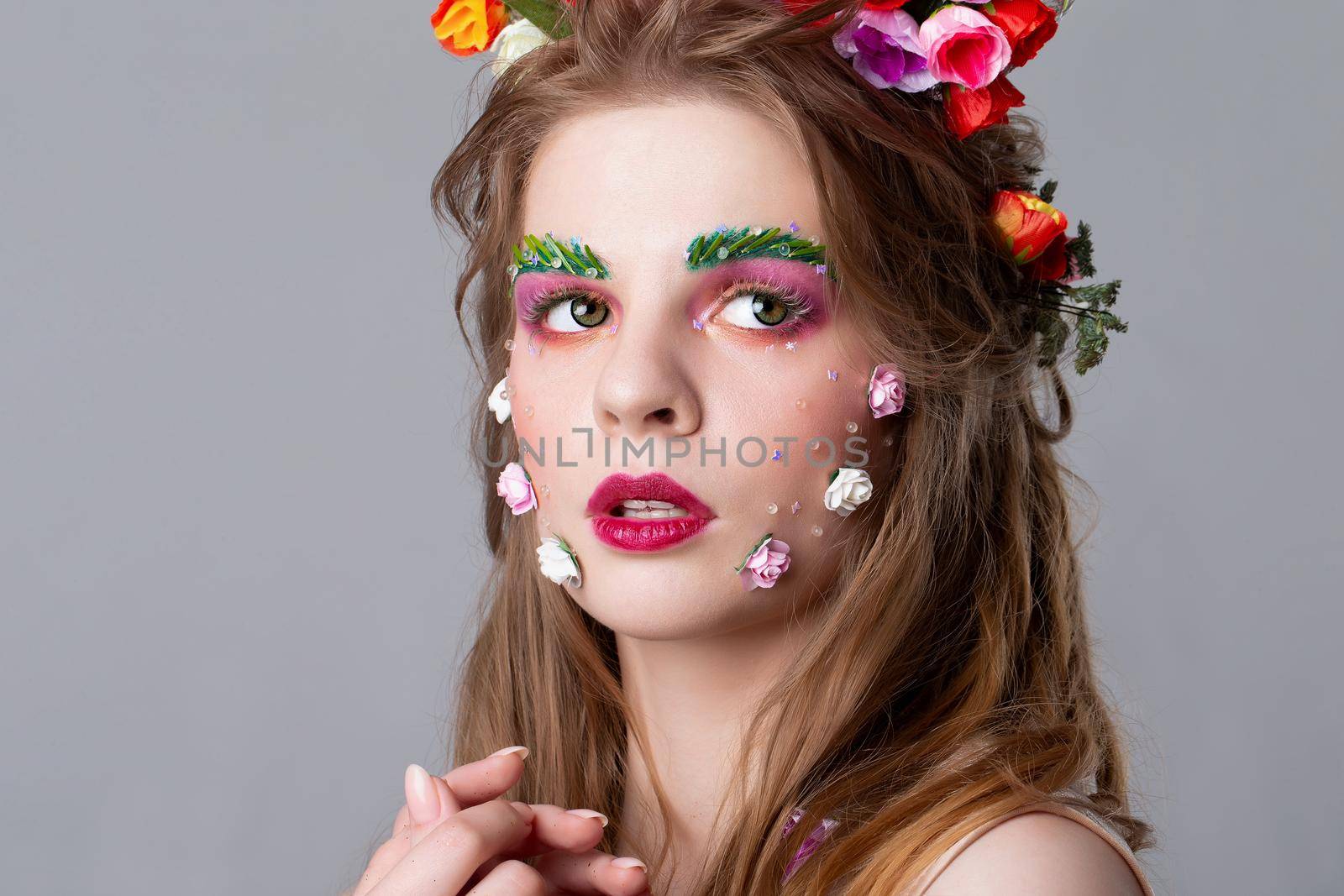 Close-up face of a beautiful girl with fairytale make-up. Spring girl. Gorgeous beauty with extended eyebrows and eyelashes. Natural cosmetics concept. The image of spring.