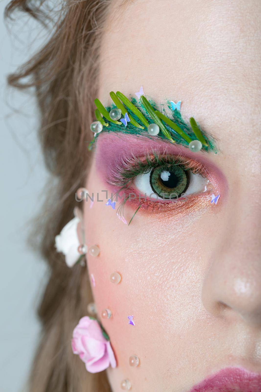 Half of the face of the girl model with extended eyebrows and eyelashes. Part of the face with bright makeup.