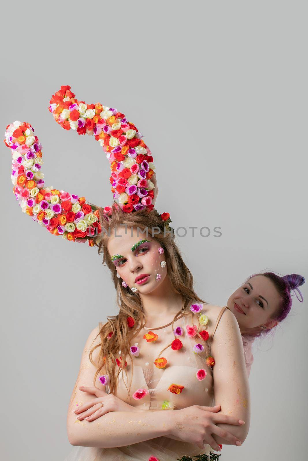 Stylist and model. Luxury girl model with flower horns and girl stylist. The work of the designer.