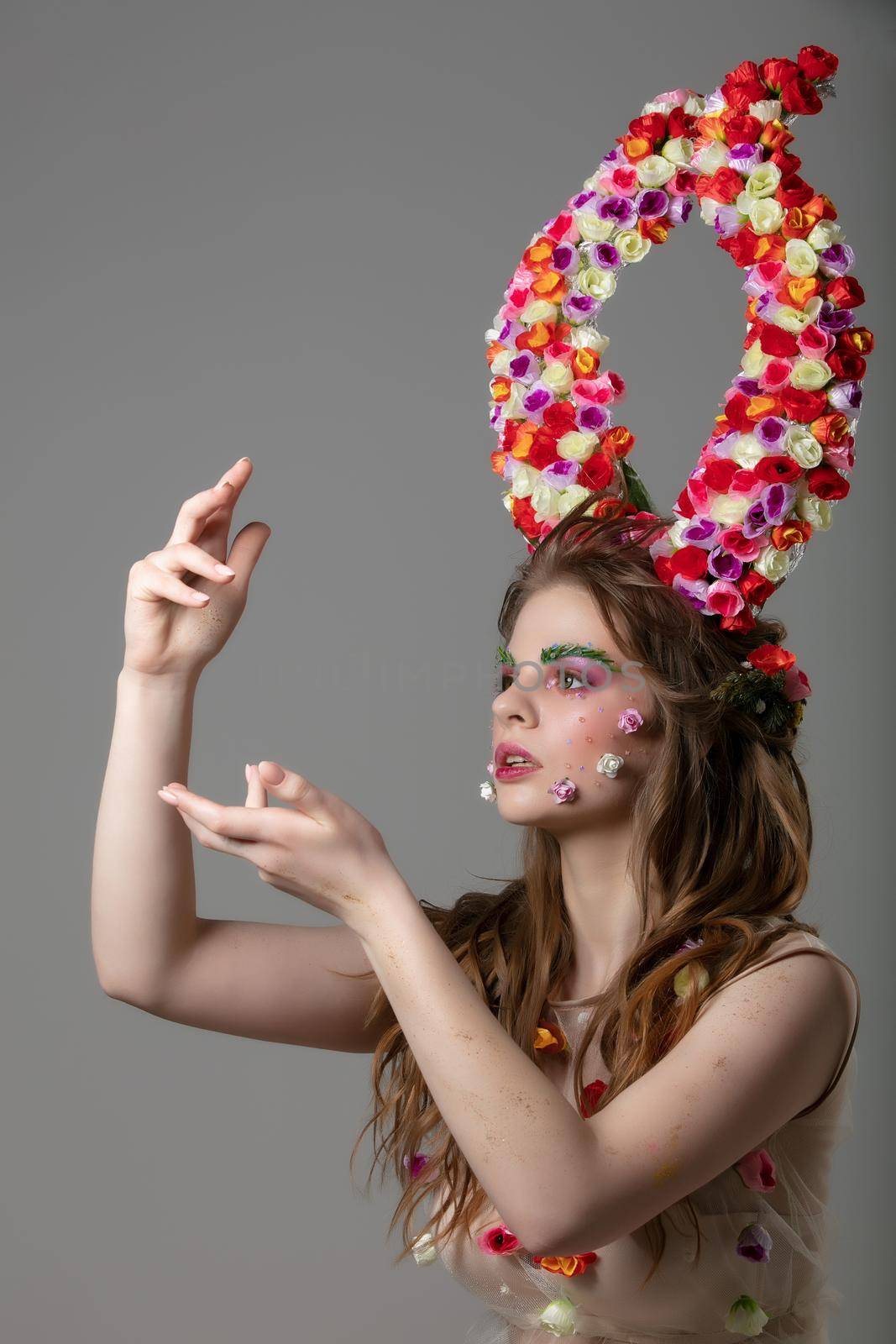 Fairytale girl with floral horns and fantastic make-up. Malifiscent. Spring or summer beauty.