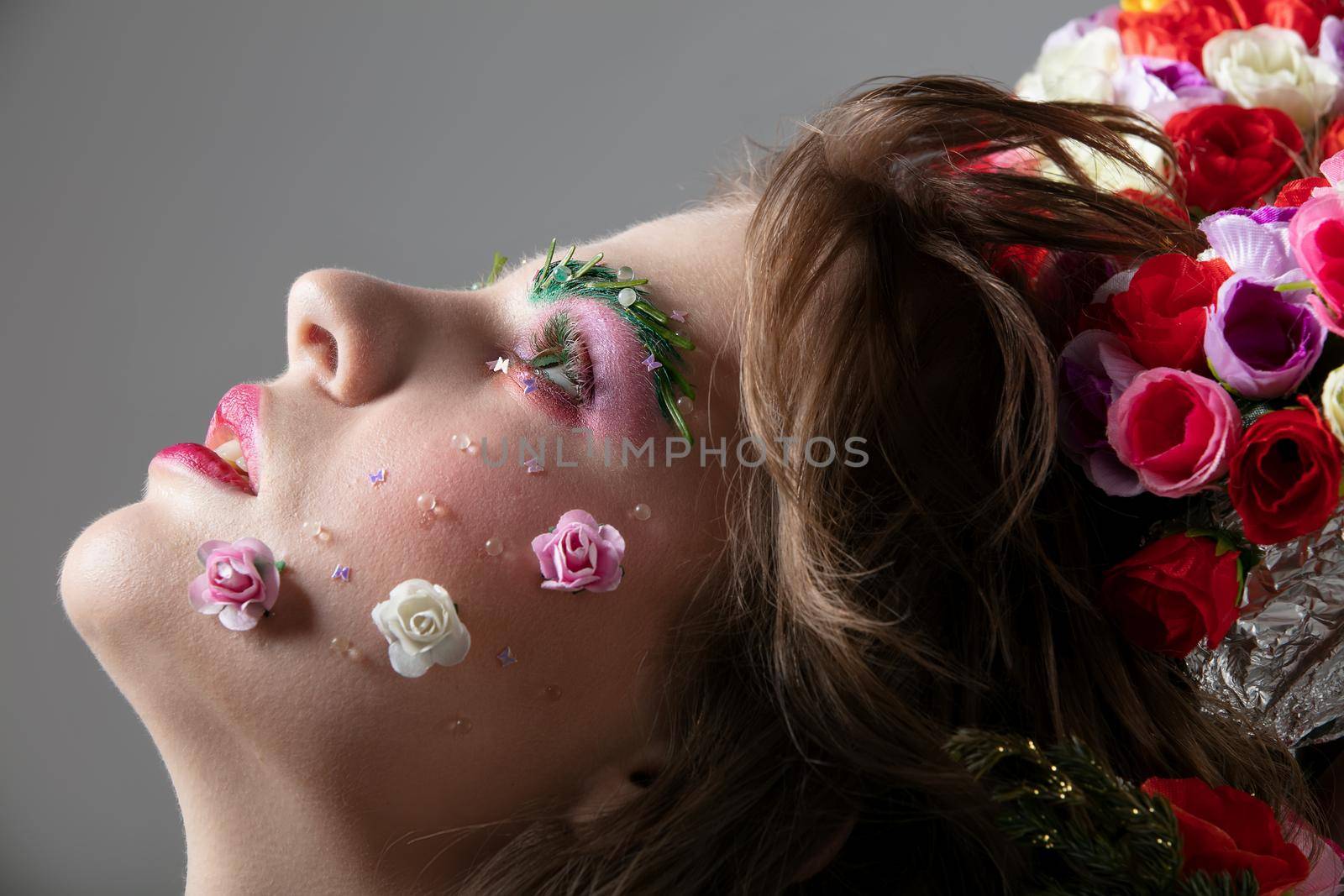 Face in profile of a girl close-up in floral makeup. Spring or summer beauty. Woman with flowers on her face.