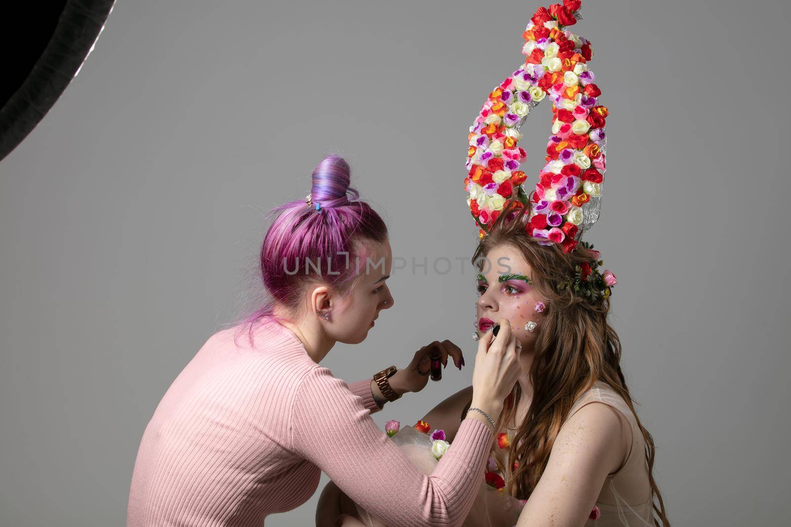 Stylist and model. Luxury girl model with flower horns and girl stylist. The work of the designer.