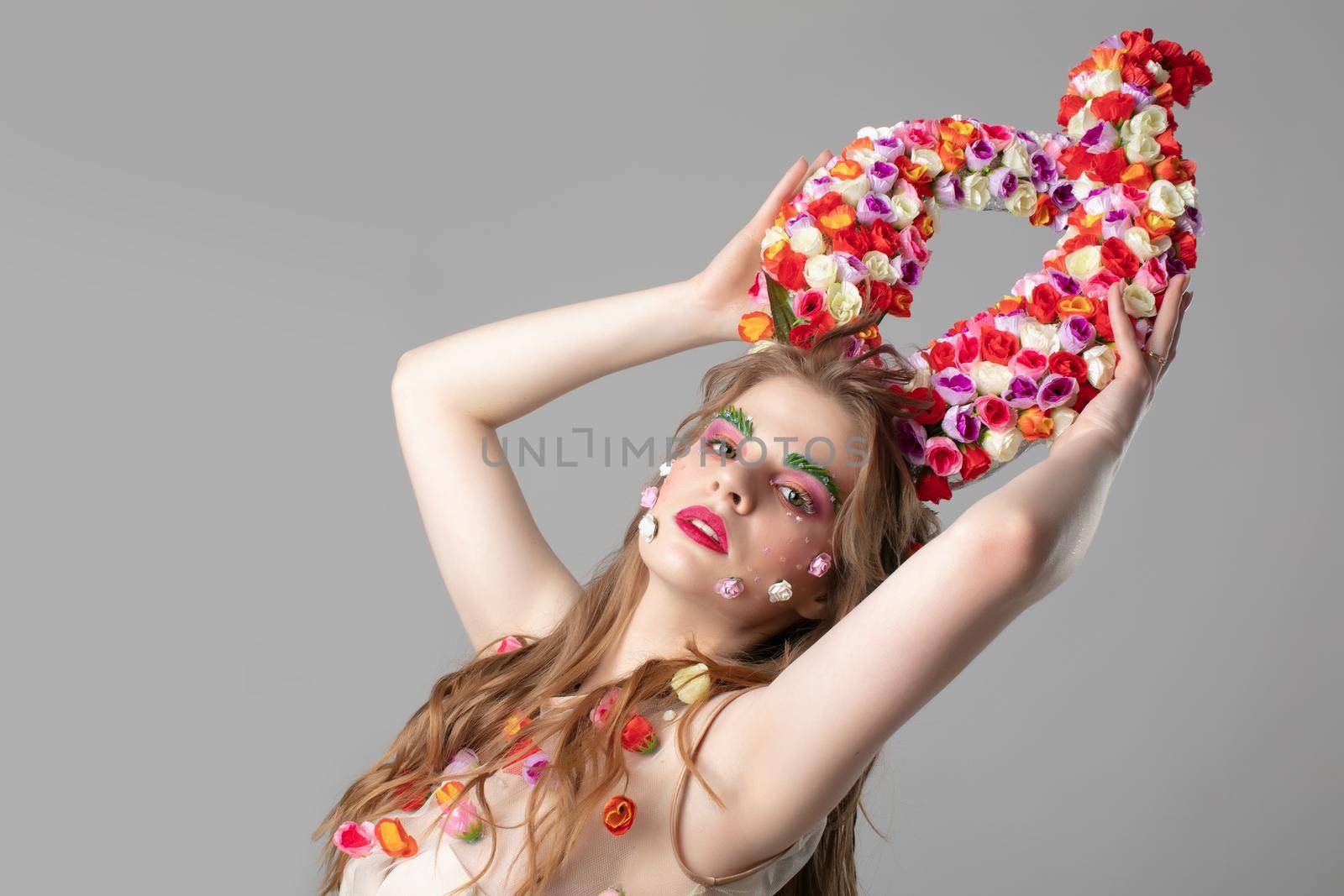 Fairytale girl with flower horns. Spring model. Beautiful girl with an unusual make-up. Hairstyle with flowers. Fantastic portrait of a beautiful woman. Summer woman. The style and image of the Malificent.