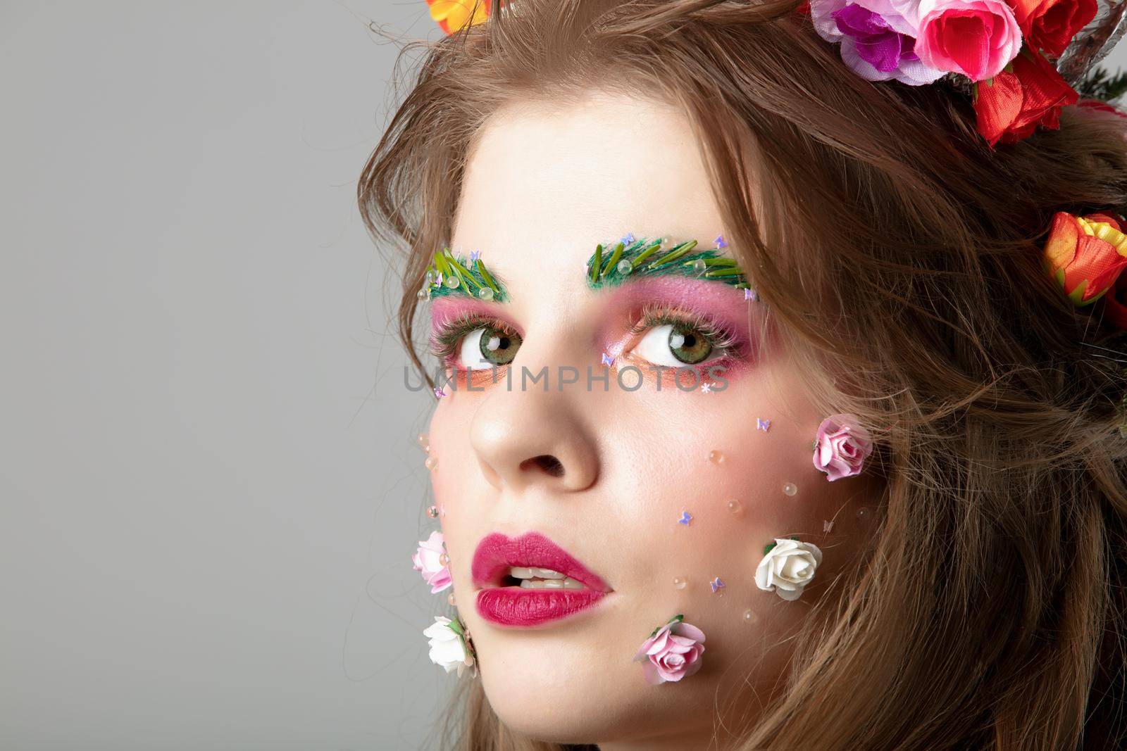 Portrait of a beautiful girl with creative make-up. Summer girl. The face of a luxurious model in flowers. Natural cosmetics concept.
