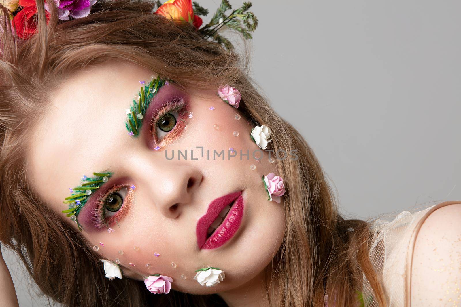 Portrait of a beautiful girl with unusual makeup. Spring girl. The face of a luxurious model in flowers. Eyebrow and eyelash extensions.