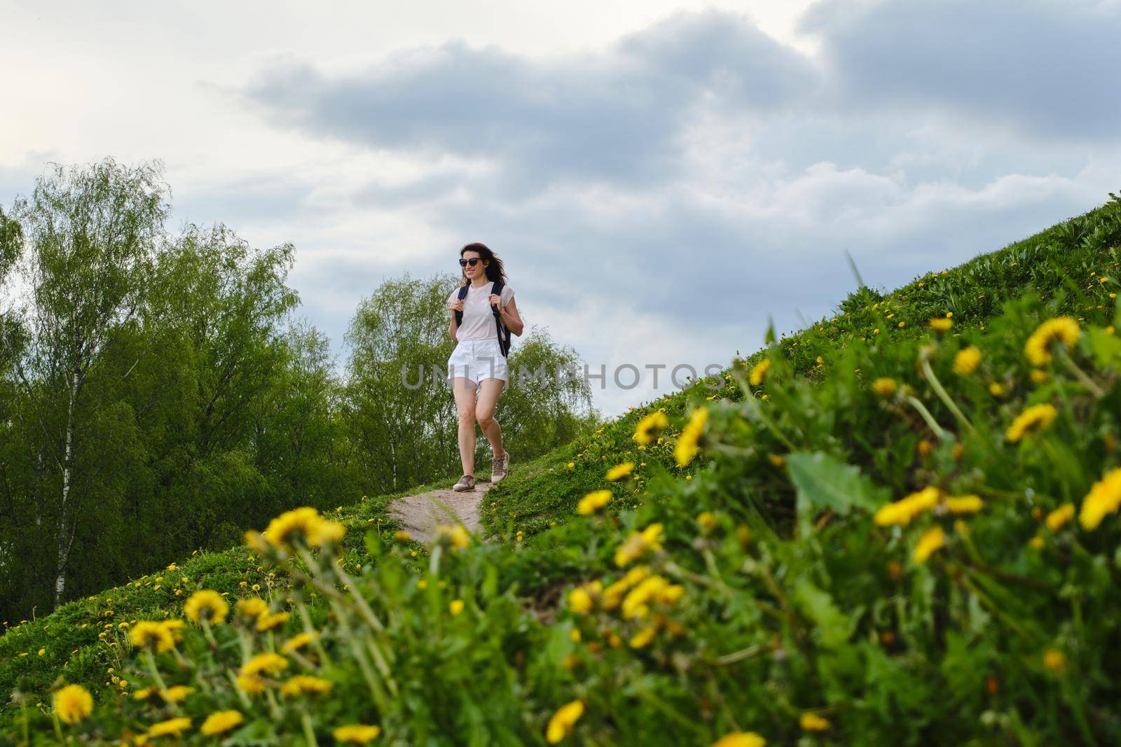 Woman walks along a path among flowers on a summer day by vollirikan