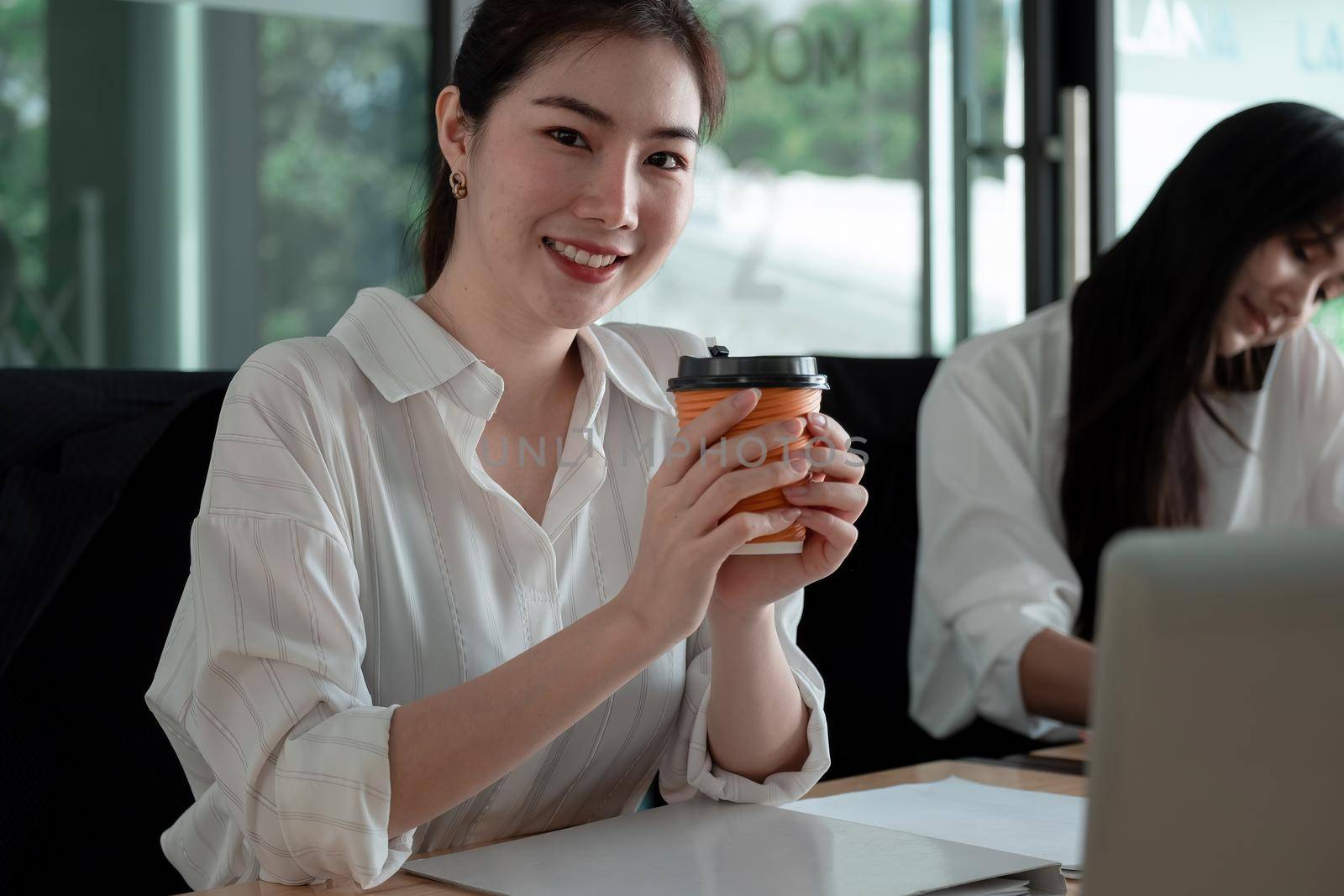 Portrait Of Attractive Asian Businesswoman Working On Laptop for marketing plan, Female hand holding a cujp of coffee by nateemee