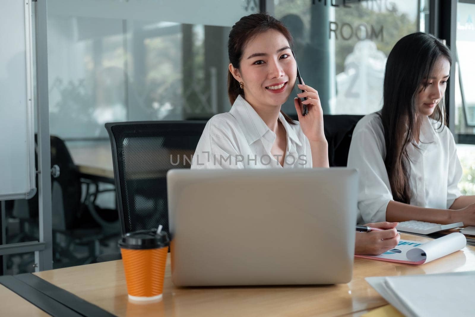 Portrait Of Attractive Asian Businesswoman Working On Laptop during call mobile phone for business strategy planning