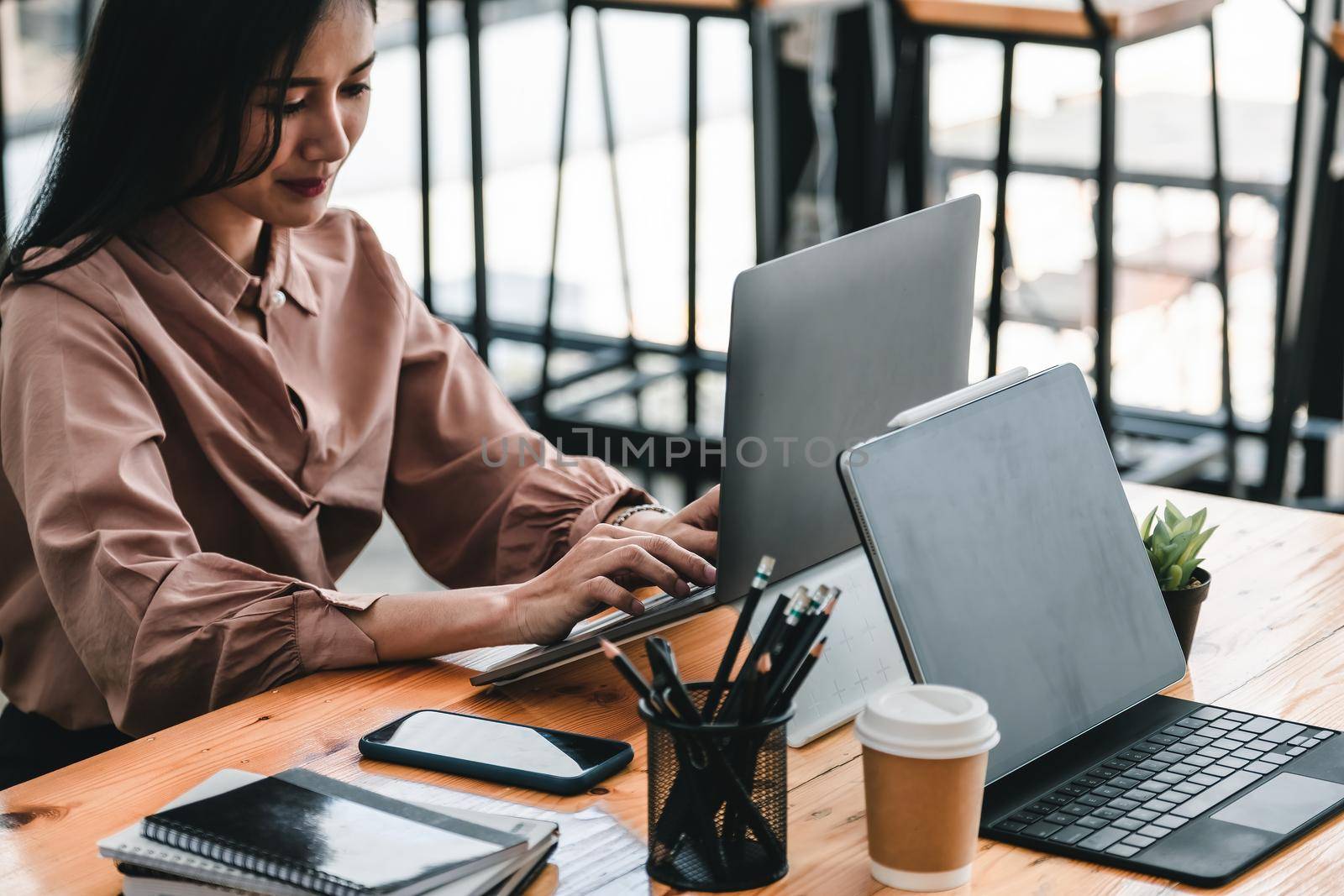 Young woman using laptop computer for business working at cafe by nateemee