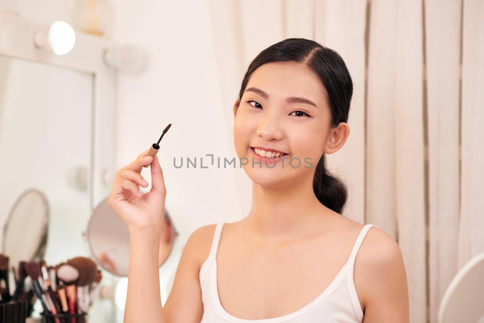 Beauty model girl applying makeup and smiling