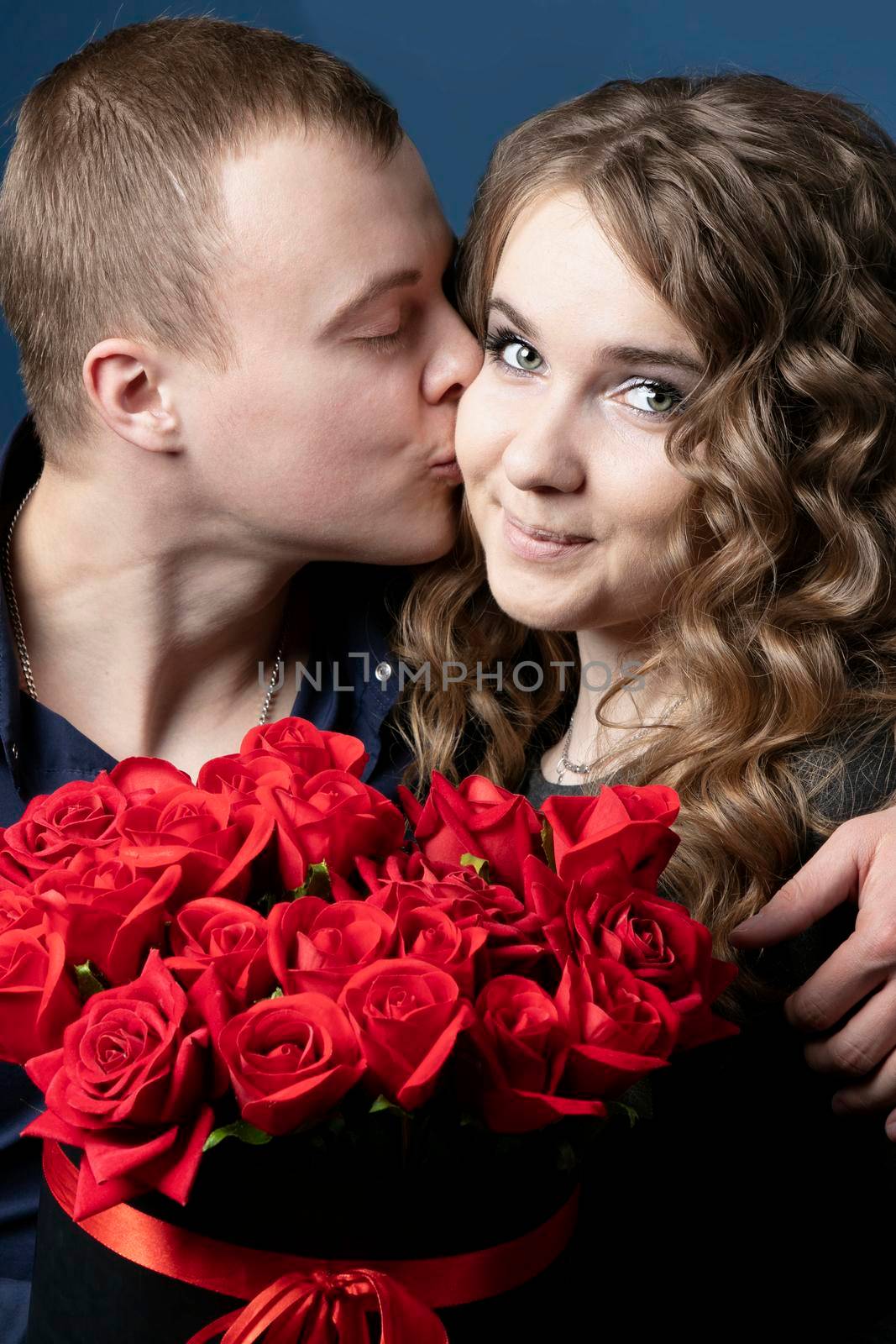 The guy and the girl with a bouquet of roses. A young couple. Lovers. A man kisses a beautiful woman.