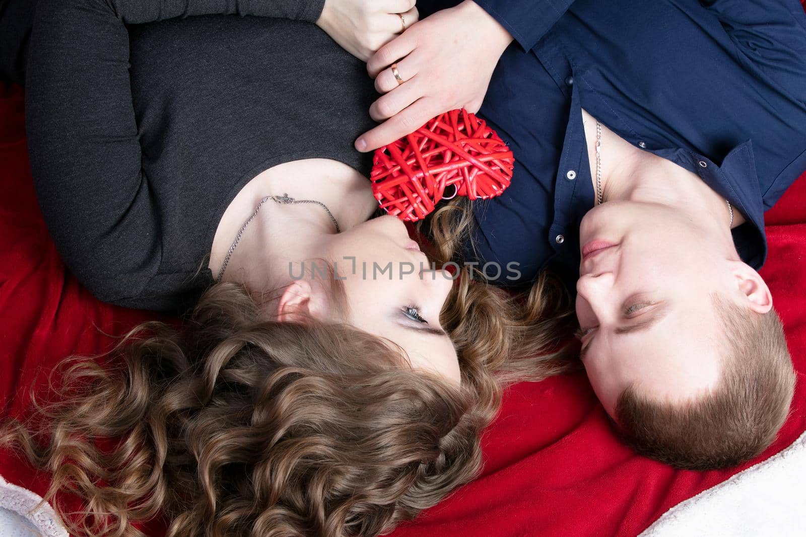 Loving couple from top to bottom. Man and woman with a red heart. Beautiful young husband and wife.Close-up man and woman together.Valentine's day. by Sviatlana