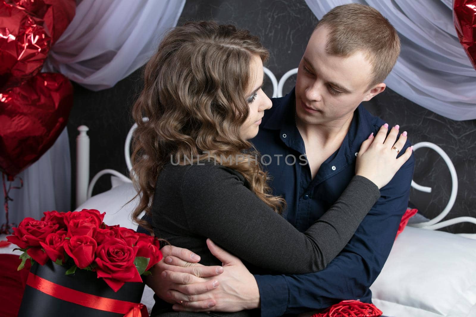 Loving couple from top to bottom. Man and woman with red roses in the bedroom. Beautiful young husband and wife.Close-up man and woman hugging.Valentine's day.