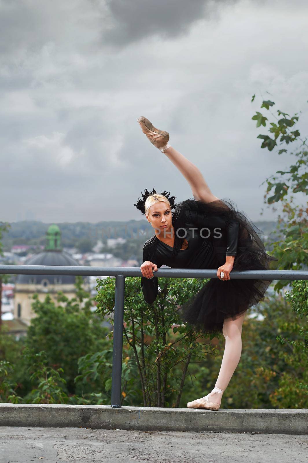 Vertical shot of a stunning young ballerina dancing in the city doing splits stretching her leg up in the air balance flexibility performance profession show.