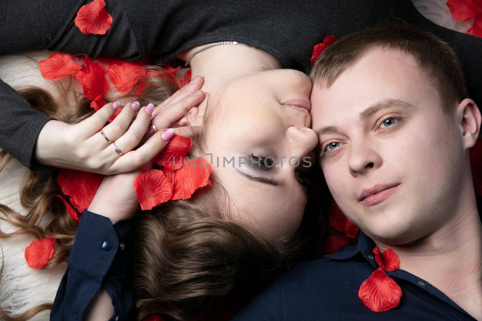 Loving couple. Man and woman in rose petals. Beautiful young husband and wife.