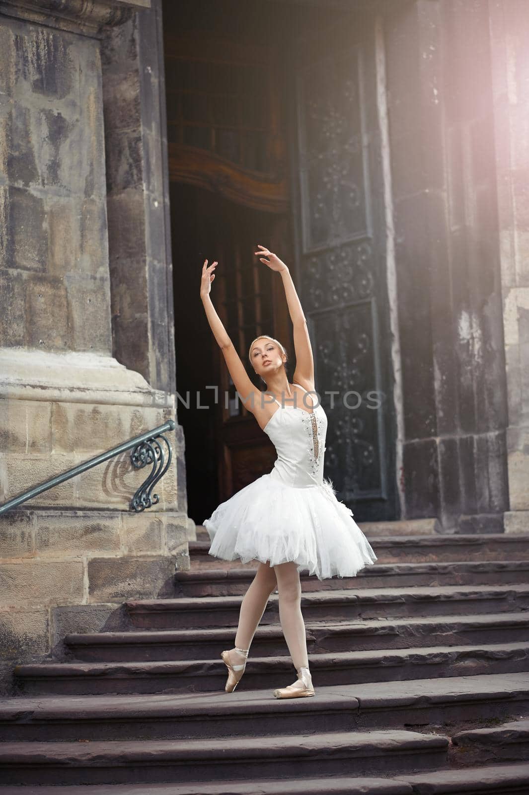 Gorgeous female ballet dancer performing outdoors dancing near and old building.