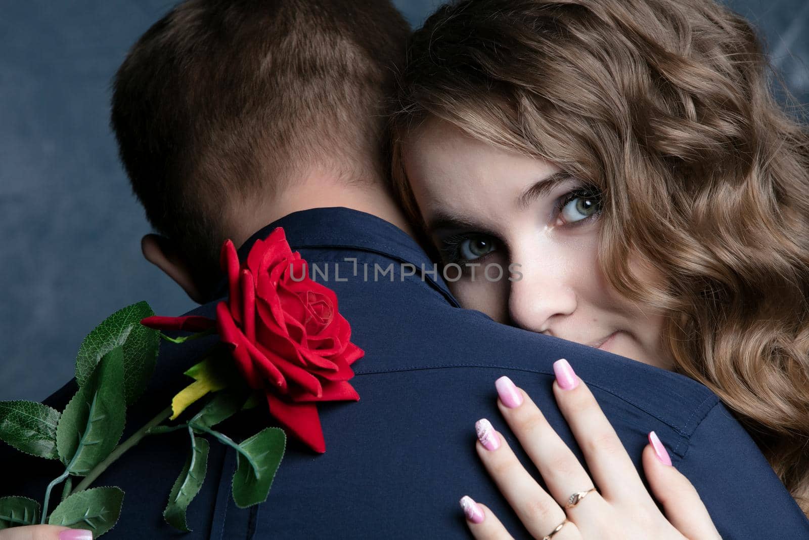 The face of a beautiful girl with a red rose on the shoulder of a guy. Valentine's Day. Lovers. Romantic date.