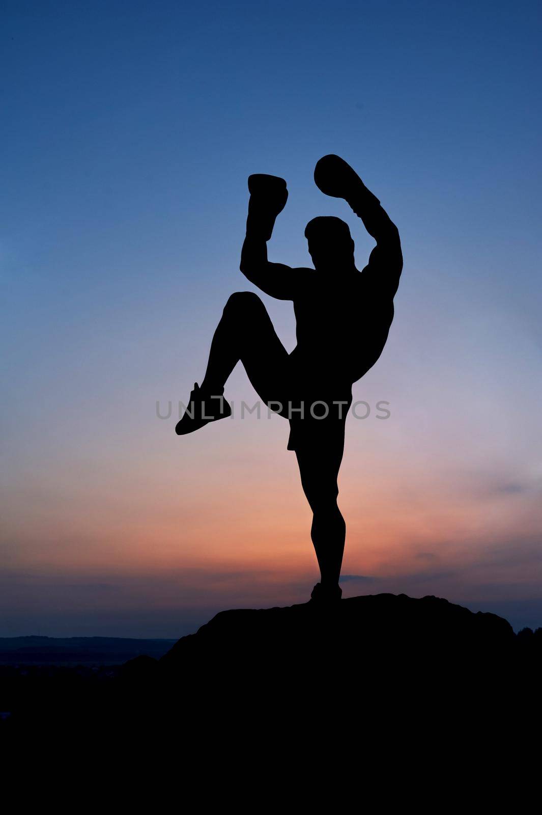 Dark silhouette of a muscular male boxer outdoors on sunset by SerhiiBobyk