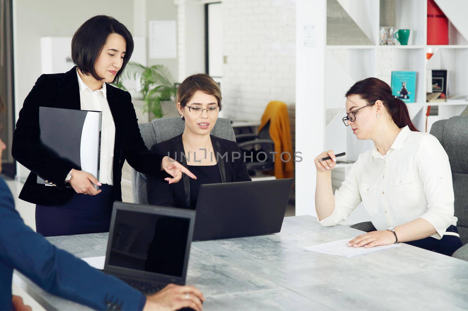 Three young successful business women in the office working together on a project by selinsmo