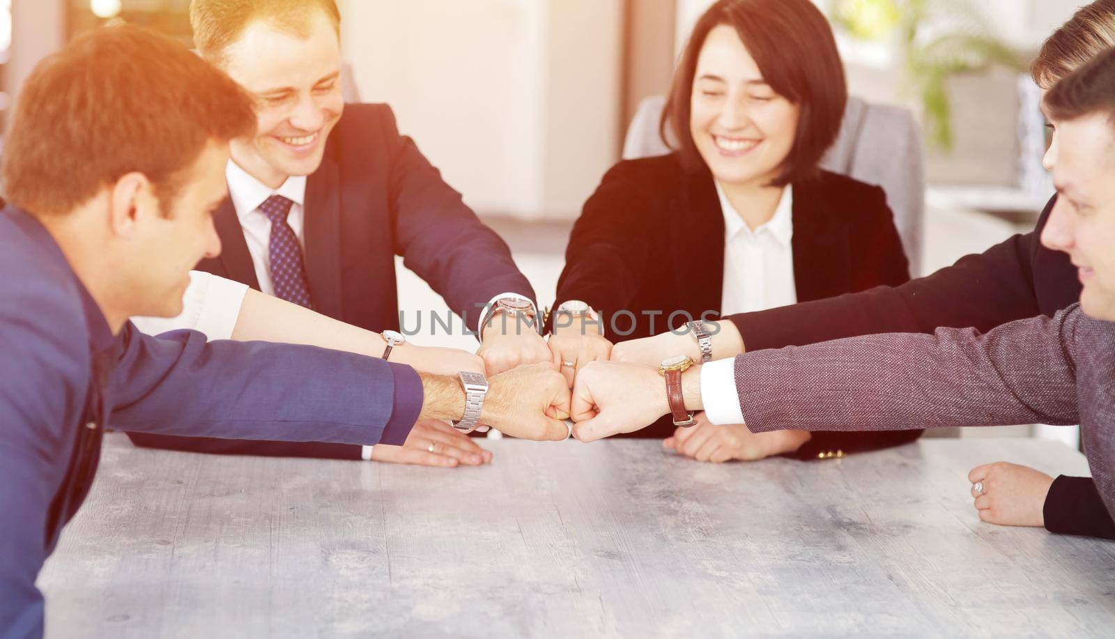 Unity and teamwork concept of young business people folding their hands together by selinsmo