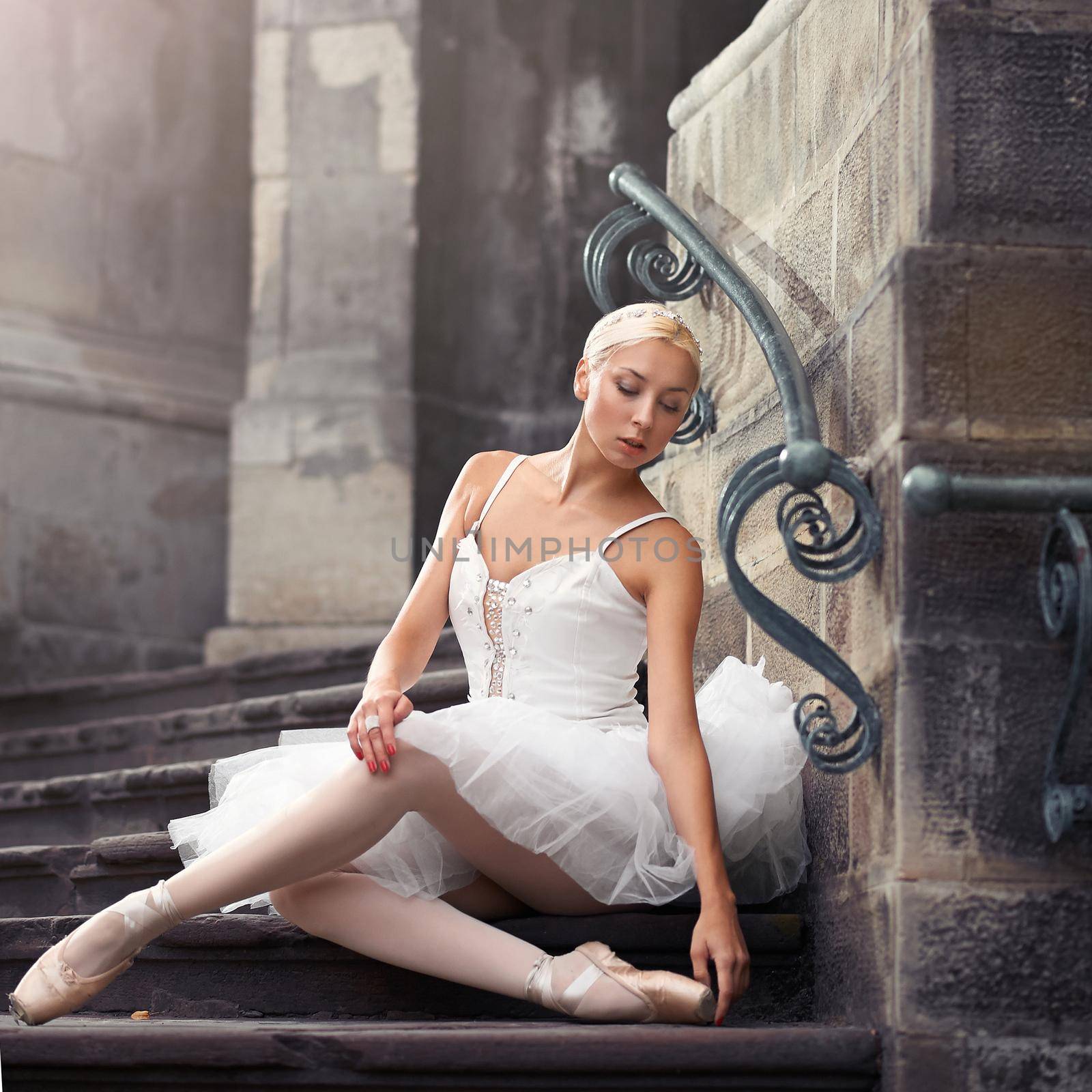 A bit of rest for the prima. Gorgeous ballerina sitting on an old stairway looking away